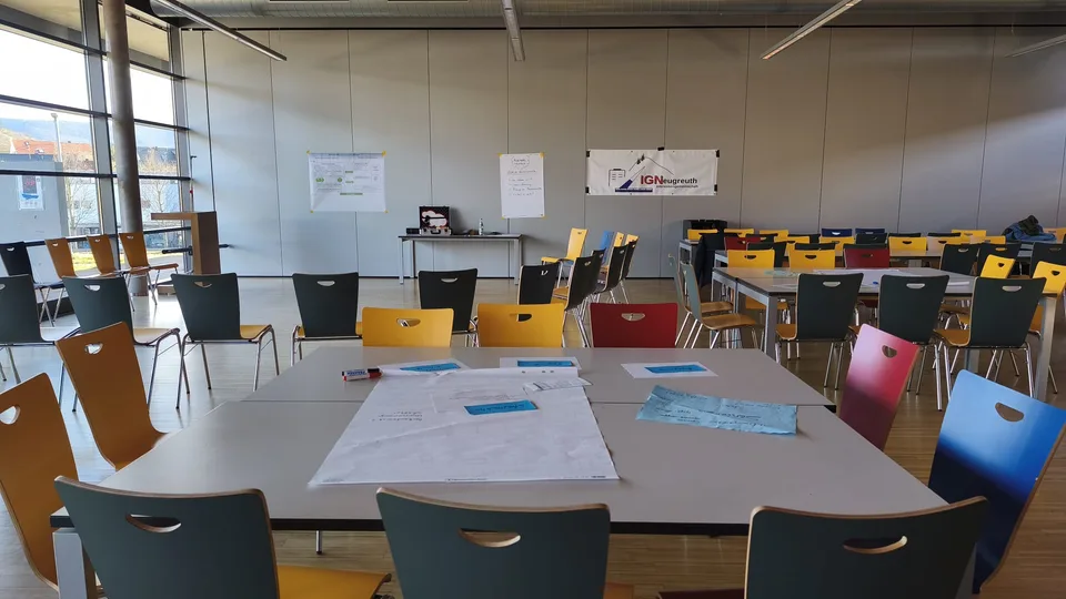 Mensa der Neugreuthschule: vorbereitete Tische und Stühle mit IGN-Banner an der Wand